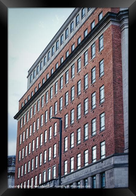 Facade of a red brick office building with multiple windows under a cloudy sky, showcasing urban architecture in Leeds, UK. Framed Print by Man And Life
