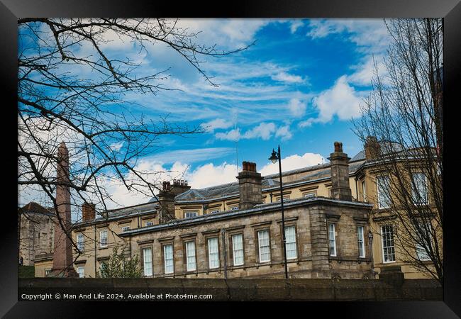 Classic European architecture with ornate details under a vibrant blue sky with fluffy clouds, framed by bare tree branches on the left in York, North Yorkshire, England. Framed Print by Man And Life