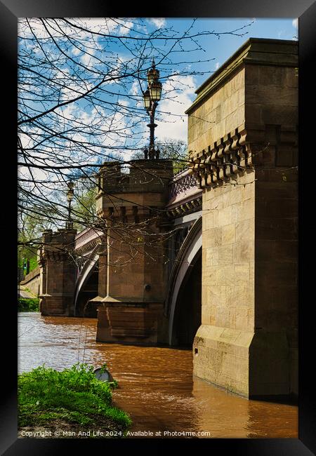 Scenic view of an old stone bridge with arches over a river, framed by blue skies and greenery, with a vintage street lamp adding to the historic charm in York, North Yorkshire, England. Framed Print by Man And Life