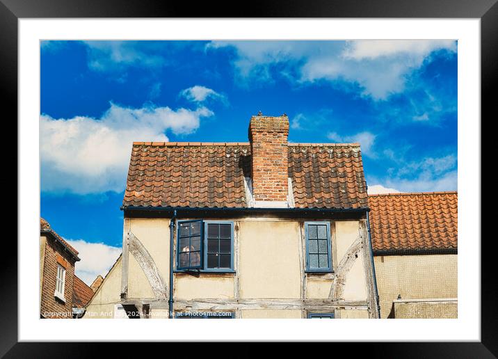Old European building with weathered facade and terracotta roof tiles against a backdrop of a vibrant blue sky with fluffy clouds in York, North Yorkshire, England. Framed Mounted Print by Man And Life