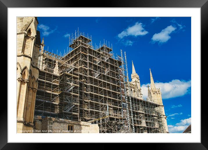 Historic cathedral undergoing renovation, with intricate scaffolding against a bright blue sky with clouds. Architectural preservation concept in York, North Yorkshire, England. Framed Mounted Print by Man And Life