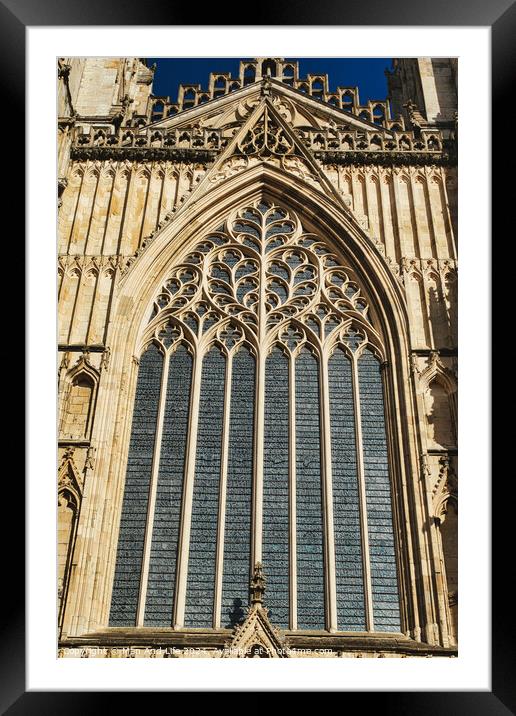 Gothic architecture detail of a cathedral window with intricate tracery and stained glass, set against a clear blue sky in York, North Yorkshire, England. Framed Mounted Print by Man And Life