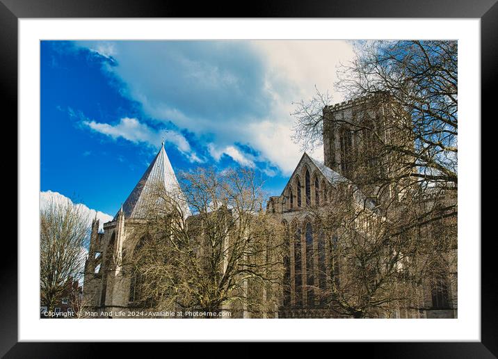 Historic medieval cathedral with Gothic architecture, featuring pointed arches and robust stone walls, set against a vibrant blue sky with fluffy clouds in York, North Yorkshire, England. Framed Mounted Print by Man And Life