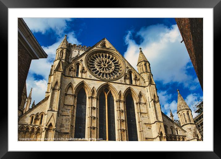 Gothic cathedral facade with rose window and spires against a blue sky with clouds, framed by trees in York, North Yorkshire, England. Framed Mounted Print by Man And Life