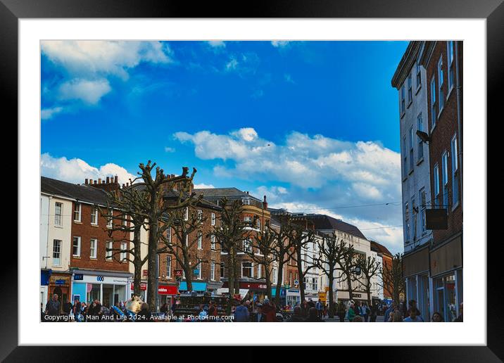 Bustling city street scene with pedestrians, unique pruned trees under a blue sky with clouds, and historic buildings, capturing the essence of urban life in York, North Yorkshire, England. Framed Mounted Print by Man And Life