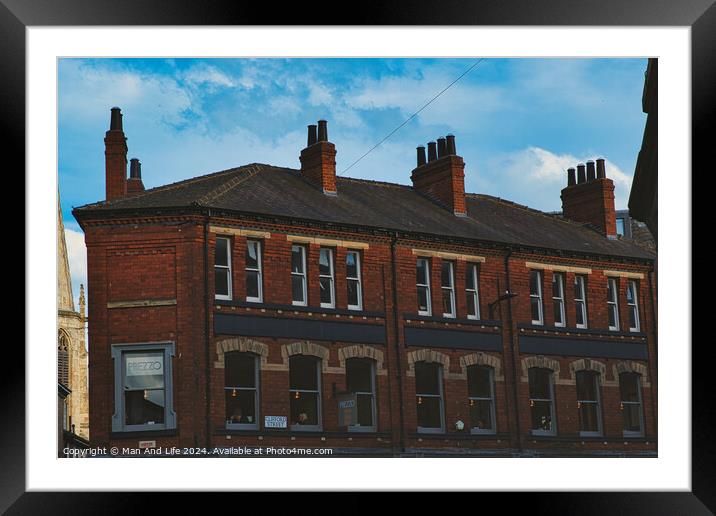 Traditional red brick building with multiple chimneys against a blue sky with light clouds, showcasing classic urban architecture in York, North Yorkshire, England. Framed Mounted Print by Man And Life