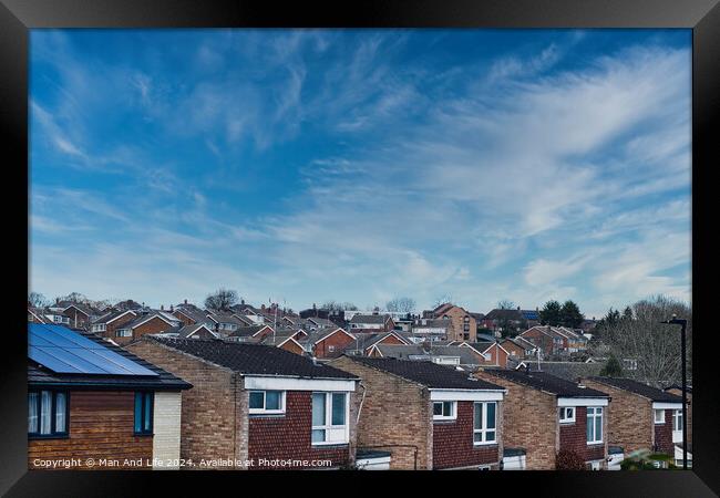 Suburban skyline with rows of houses and solar panels on a roof under a blue sky with wispy clouds in Harrogate, North Yorkshire. Framed Print by Man And Life