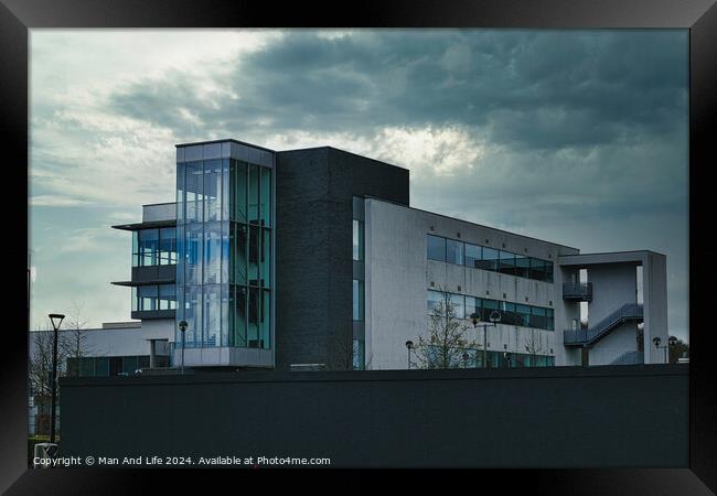 Modern office building against a dramatic cloudy sky, showcasing contemporary architecture with a mix of glass and concrete elements. Framed Print by Man And Life