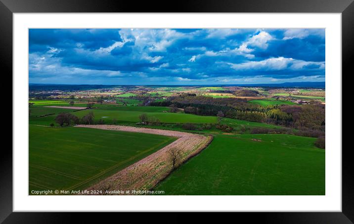 Vibrant aerial view of a lush countryside with patchwork fields under a dramatic sky, showcasing the beauty of rural landscapes and the diversity of agriculture. Framed Mounted Print by Man And Life