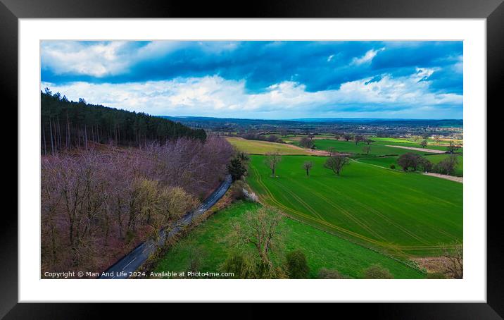Aerial view of a vibrant rural landscape with a road running alongside a forest, contrasting green fields and a dramatic cloudy sky. Framed Mounted Print by Man And Life