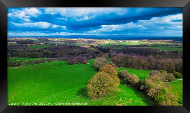 Vibrant aerial landscape with lush green fields, scattered trees, and a dramatic sky with fluffy clouds casting shadows over the countryside. Framed Print by Man And Life