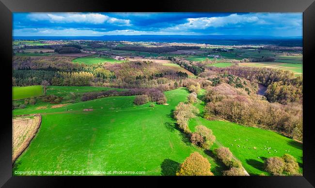 Aerial view of a vibrant rural landscape with lush green fields, patches of forests, and a clear view extending to the horizon under a partly cloudy sky. Framed Print by Man And Life