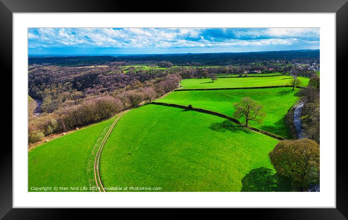 Aerial view of lush green countryside with fields, trees, and a winding path under a blue sky with scattered clouds. Framed Mounted Print by Man And Life