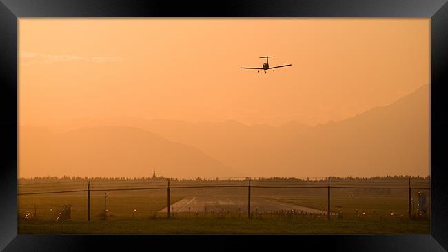 Light airplane landing at sunset Framed Print by Ian Middleton