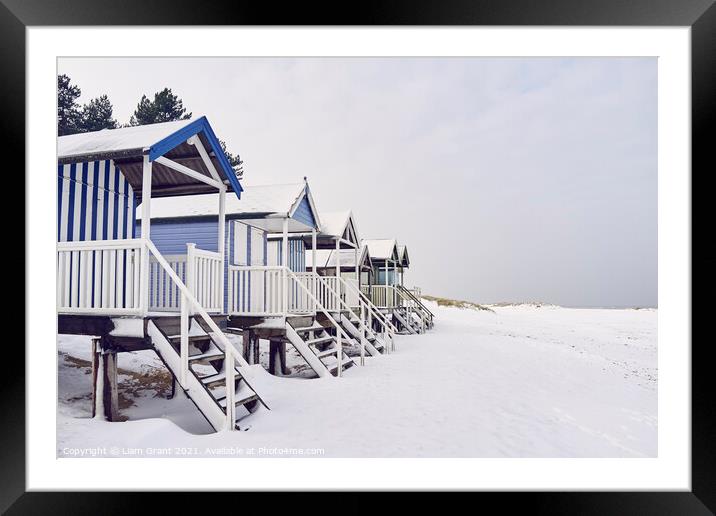 Beach huts covered in snow at low tide. Wells-next-the-sea, Norf Framed Mounted Print by Liam Grant
