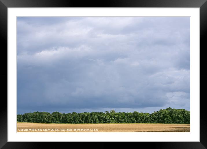 Dramatic rainclouds over rural field Framed Mounted Print by Liam Grant