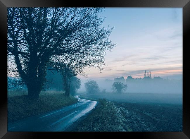 Evening sky over rural road leading into fog. Framed Print by Liam Grant