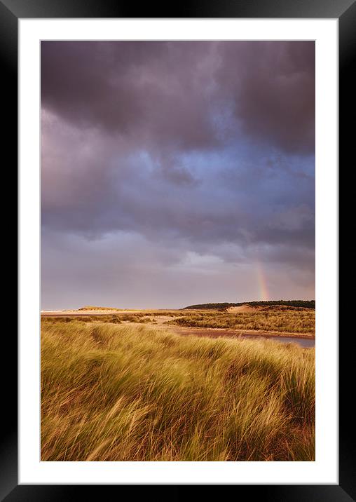 Storm clouds and rainbow at sunset. Holkham, Norfo Framed Mounted Print by Liam Grant