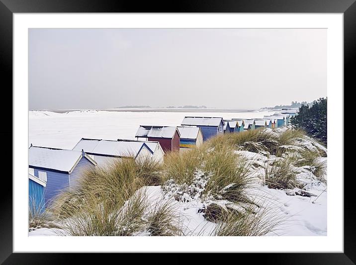 Beach huts and dunes covered in snow at low tide.  Framed Mounted Print by Liam Grant