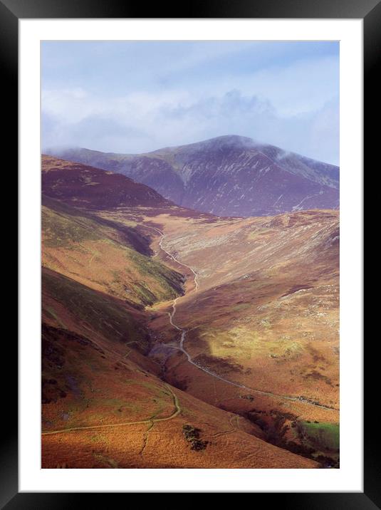 Distant tracks leading up a mountainside in Autumn Framed Mounted Print by Liam Grant