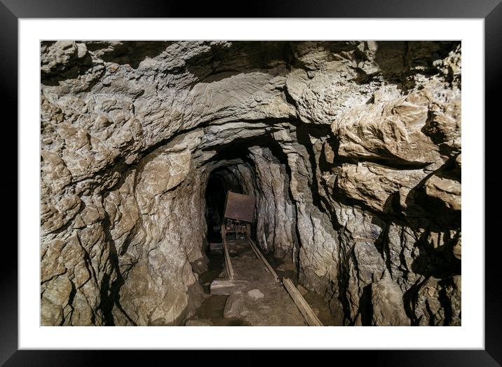 Mine cart in an old abandoned mine cave. Near Matl Framed Mounted Print by Liam Grant