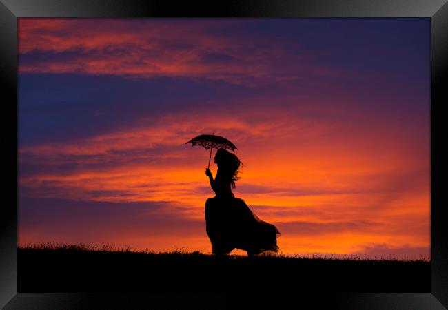 Silhouette of young woman running at sunset Framed Print by Maggie McCall