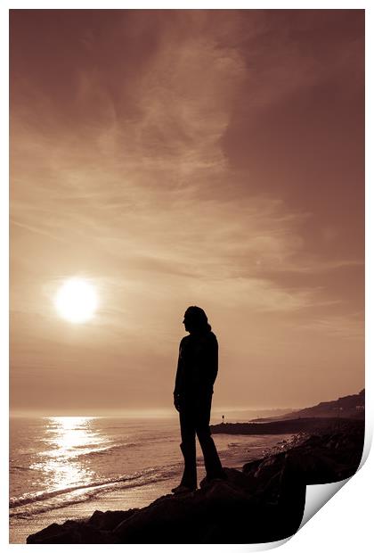 Silhouetted girl stands by sea at sunset Print by George Cairns