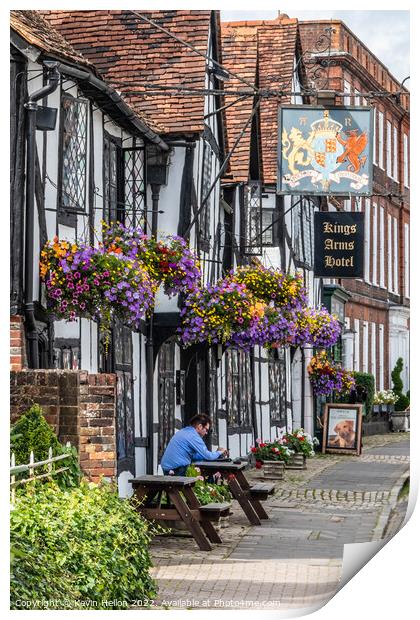 A man sits outside the Kings Arms Hotel in Amersham old town Print by Kevin Hellon