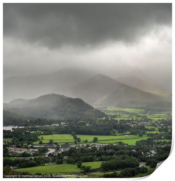 Stunning epic landscape image across Derwentwater valley with falling rain drifting across the mountains causing pokcets of light and dark across the countryside Print by Matthew Gibson