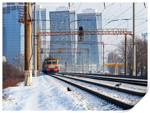 An old electric train moves on rails against the backdrop of a cityscape of skyscrapers on a sunny winter day. Print by Sergii Petruk