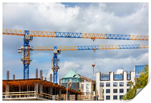 Construction site with tower cranes and the construction of a residential building against the backdrop of a cloudy sky. Print by Sergii Petruk
