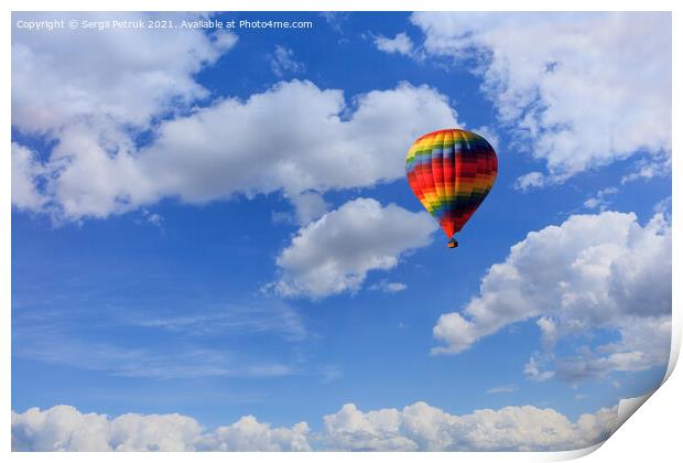 A motley multicolored hot air balloon raises a basket with tourists in the blue sky among white clouds. Print by Sergii Petruk