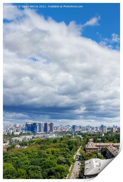 A large white and gray cloud loomed over a green park in the old residential area of the city and new buildings on the horizon against the backdrop of a bright summer day. Print by Sergii Petruk