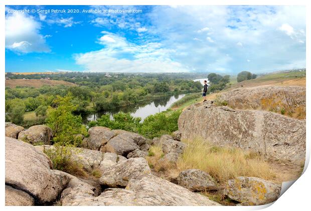 The teenager stands on top of a large stone boulder on the bank of the Southern Bug River and looks at the river below Print by Sergii Petruk