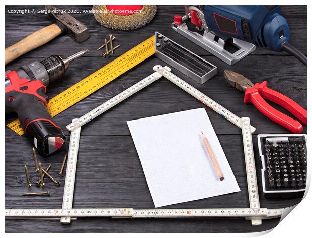 Tool for construction and repair on a black wooden background around a white sheet of paper with a pencil Print by Sergii Petruk