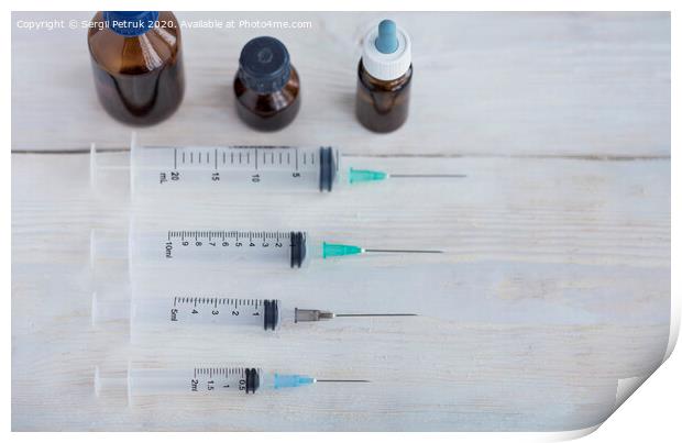 Syringes and capsules, medical ampoules on a white wooden table. Print by Sergii Petruk