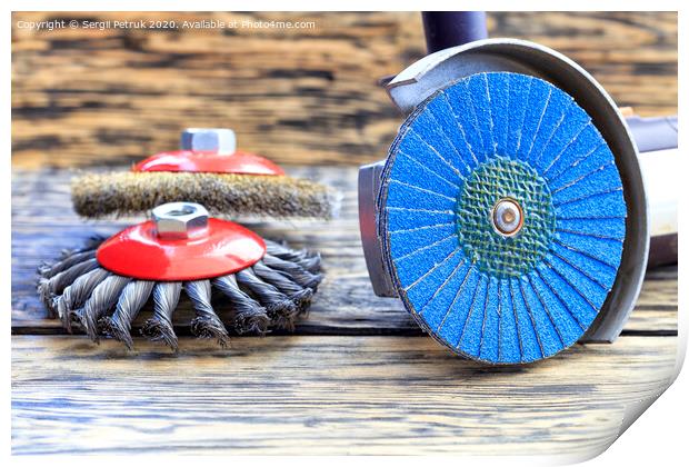 Angle grinder with grinding disc brushes lies on the background of a wooden table. Print by Sergii Petruk
