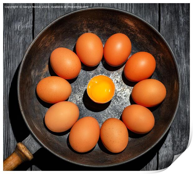 Brown chicken eggs in an old cast-iron frying pan look in the center at a broken egg with a bright yolk. Print by Sergii Petruk