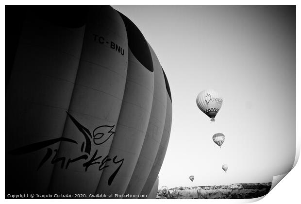 Goreme, Turkey - April 4, 2012: Hot air balloons for tourists flying over rock formations at sunrise in the valley of Cappadocia. Print by Joaquin Corbalan