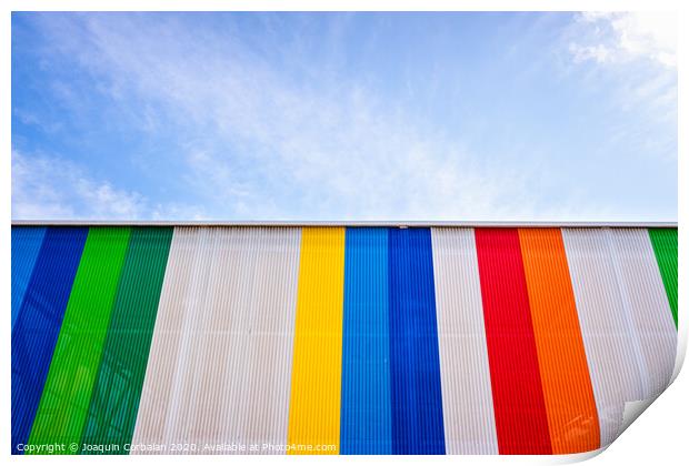 Facade with colored lines, against the blue sky in the background. Print by Joaquin Corbalan