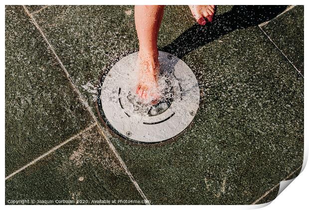Young barefoot boy running through squirting water in a pool in a spa. Print by Joaquin Corbalan