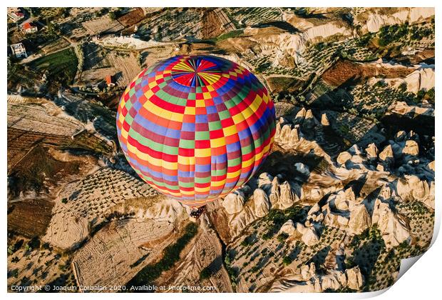 Travelers and tourists flying over mountains at sunset in a colorful aerostat balloon in Goreme, the Turkish cappadocia. Print by Joaquin Corbalan