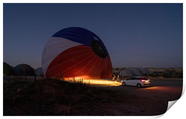 A car parked in front of a hot air balloon with headlights on during night, preparation of a flight in Goreme national park in Cappadocia, Turkey Print by Arpan Bhatia