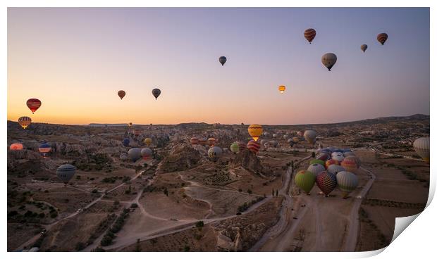 Cappadocia, Turkey - September 14, 2021: Wide angle aerial panoramic shot of colorful hot air balloons together floating in the sky at early morning sunrise horizon in Goreme national park Print by Arpan Bhatia