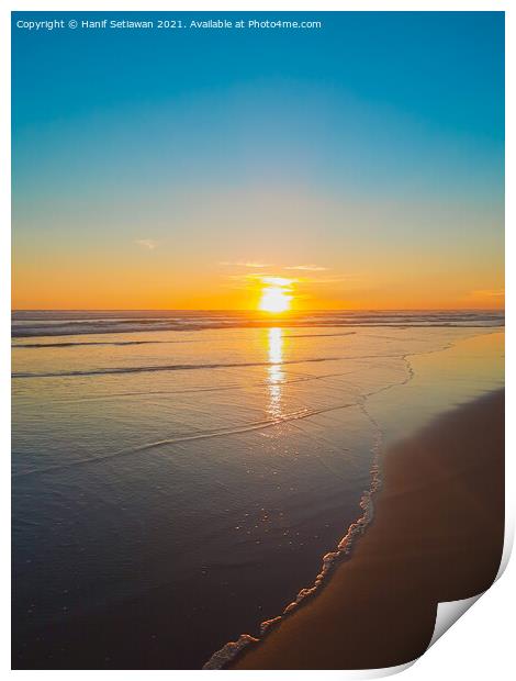 Wide sand beach reflecting orange sunset sunlight. Print by Hanif Setiawan