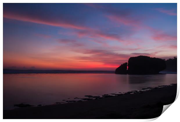 Silhouetted reflecting rock at sunset on sandbeach Print by Hanif Setiawan