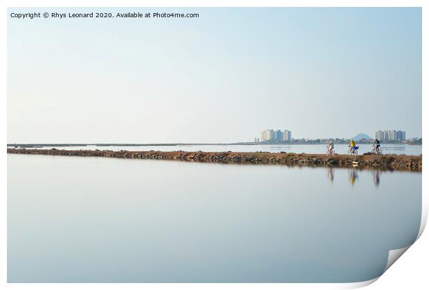 Reflections of 3 pedal bike riders shimmering over a lagoon near san pedro del pinatar in spain. Print by Rhys Leonard