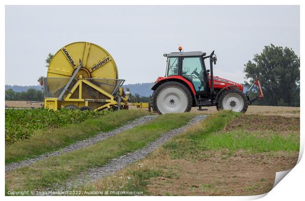 A red farm tractor with a yellow trailer at work on a field Print by Ingo Menhard
