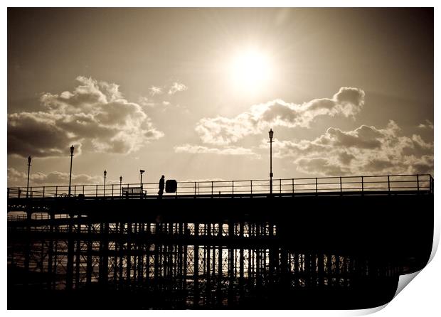 Sepia image of part of Southend Pier shot against the sun, with silhouette of structure and a man on the walkway. Southrnd on Sea, Essex. Print by Peter Bolton