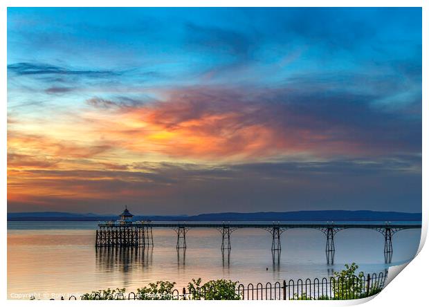 Clevedon Pier with the setting sun lighting up the cloud cover Print by Rory Hailes
